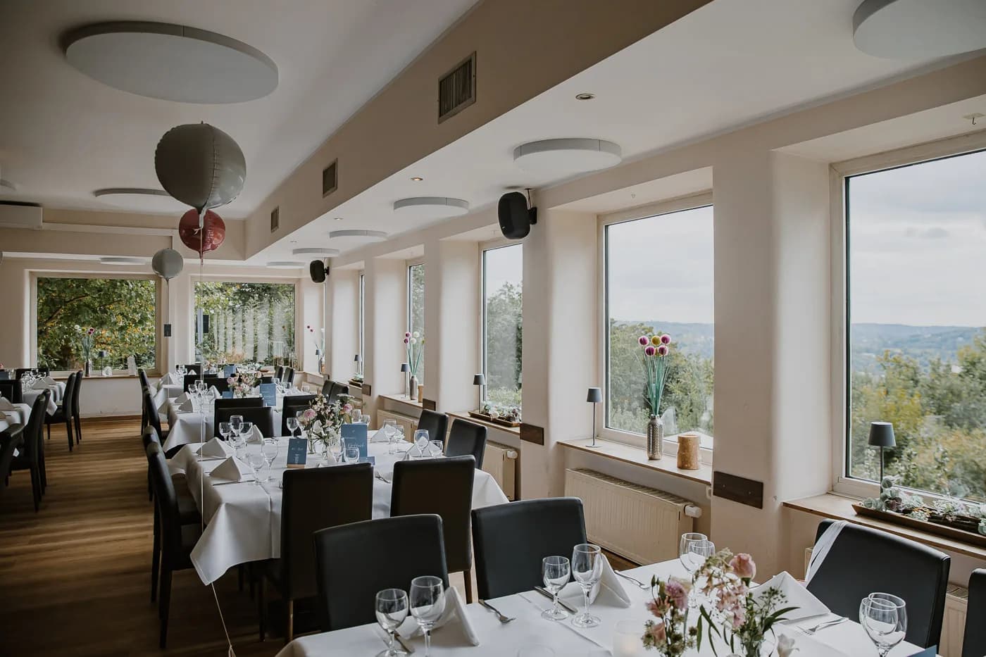 Elegant eingedeckte Festtafel mit Blumenschmuck und Panoramablick auf den Baldeneysee