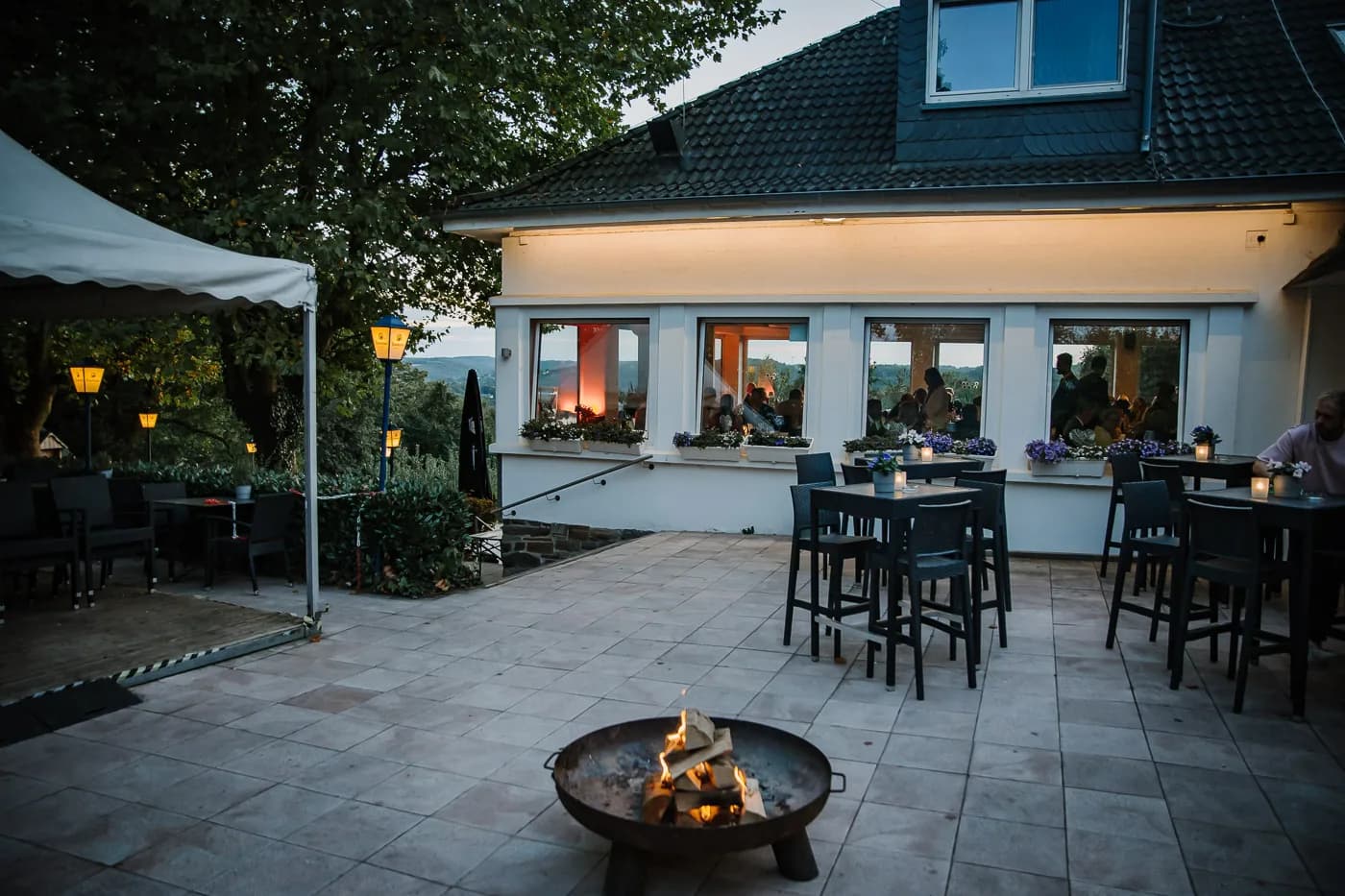 Terrasse am Abend mit brennender Feuerschale und beleuchteten Laternen